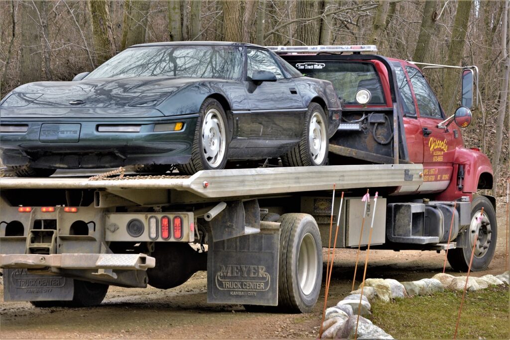 corvette, broken, needs repair, on truck, nature, vehicle, transport, automobile, sports car, hauled, remote, woods, forest, boondocks, large, wide, tires, powerful, fast car, going to repair shop, truck hauler, flatbed, flatbed hauler, brown car, brown shop, brown truck, brown power service in Conroe Texas and Montgomery County